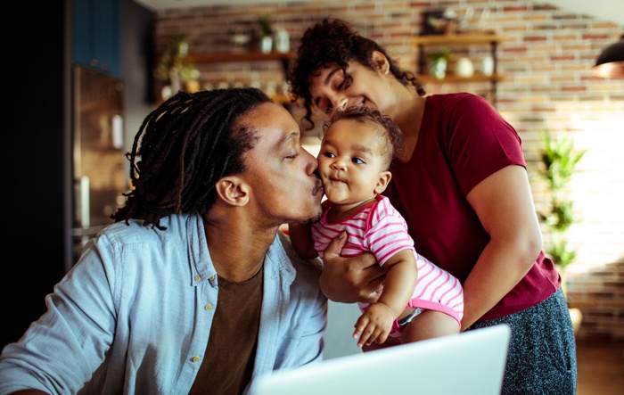 mom holding baby dad giving baby a kiss